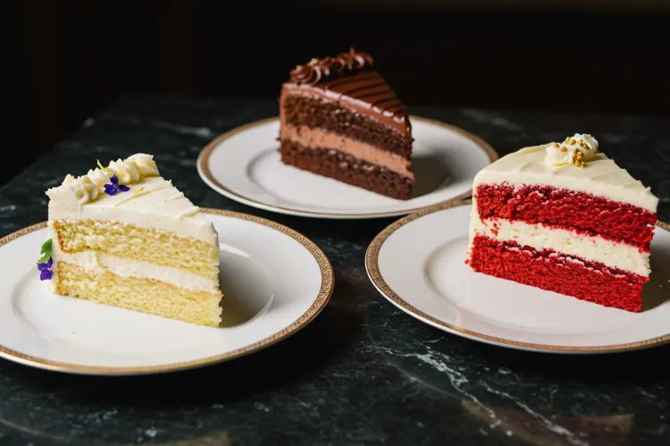 Variety of wedding cake slices on elegant plates, including vanilla, chocolate, red velvet.