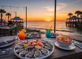 Orange Beach Alabama waterfront restaurants at sunset, seafood table with shrimp, oysters, and cocktails, beach view