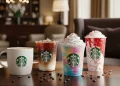 Assorted Starbucks drinks on a café table including hot coffee, iced coffee, colorful Frappuccino.