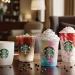 Assorted Starbucks drinks on a café table including hot coffee, iced coffee, colorful Frappuccino.