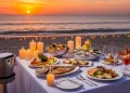 “Tropical Aruba beach sunset, luxury dining table on sand with candles, seafood dishes, ocean waves