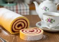 “Golden spiral jelly roll cake dusted with sugar, sliced to show jam swirl, soft natural light, rustic kitchen table, tea setting, high detail food photography”
